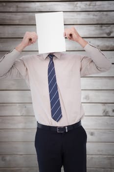 Businessman showing card in front of his head against wooden planks