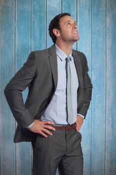 Smiling businessman with hands on hips against wooden planks