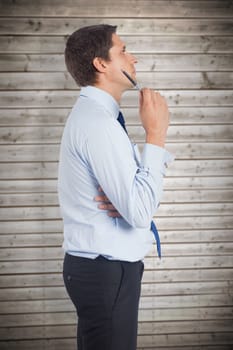 Thinking businessman holding pen against wooden planks background