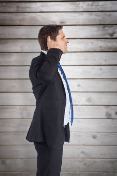 Thinking businessman scratching head against wooden planks