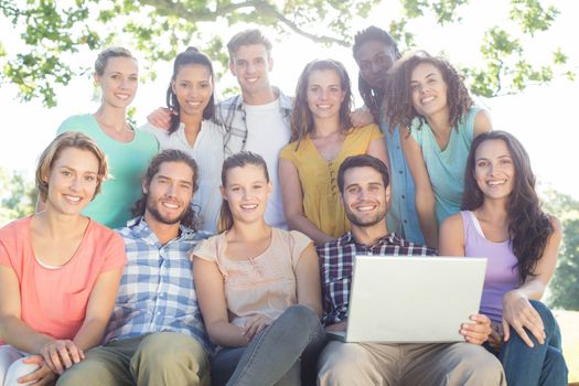 Friends looking at laptop in the park on a sunny day