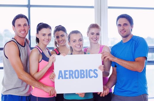 The word aerobics against portrait of a group of fitness class holding blank paper