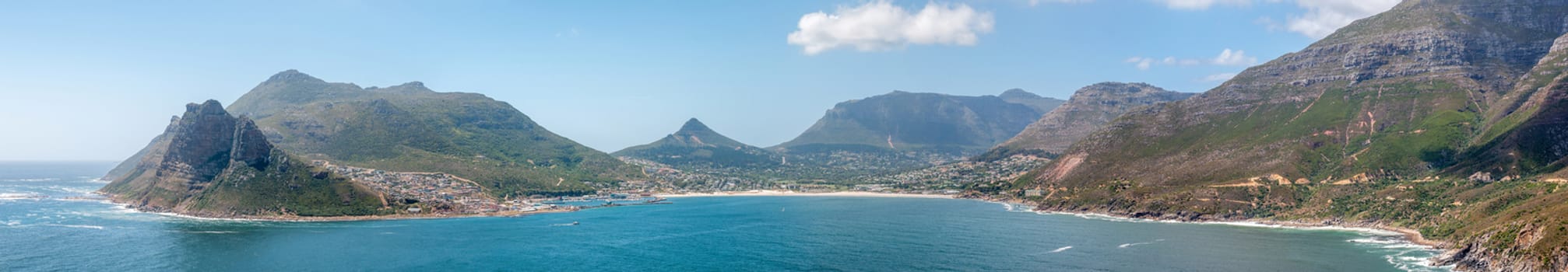 Panorama of Hout Bay harbor and town. Chapmans Peak Drive is visible to the right