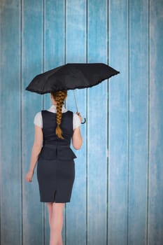 Pretty redhead businesswoman holding umbrella against wooden planks