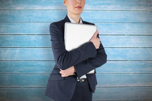 Businesswoman holding laptop against wooden planks