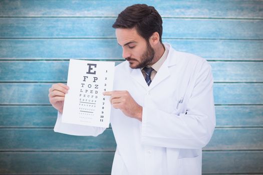 Doctor in lab coat showing eye test against wooden planks