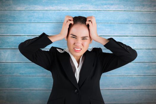 Stressed businesswoman with hands on her head against wooden planks