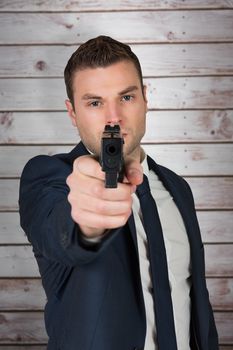 Serious businessman pointing a gun against wooden planks