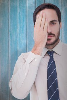 Unsmiling patient looking at camera with one eye  against wooden planks