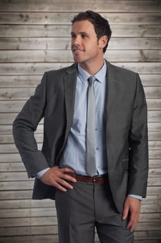 Smiling businessman with hand on hip against wooden planks background