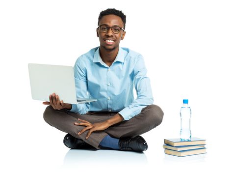 Happy african american college student with laptop, books and bottle of water sitting on white background