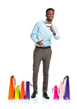 Happy african american man with shopping bags and holding credit card on white. Holidays concept