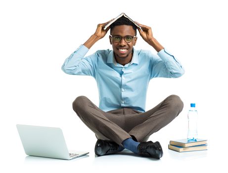 Happy african american college student with laptop, books and bottle of water sitting on white background