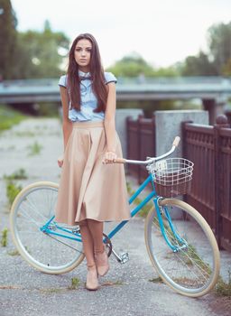 Young beautiful, elegantly dressed woman with bicycle outdoor. Beauty, fashion and lifestyle