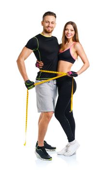 Happy athletic couple - man and woman with measuring tape on the white background