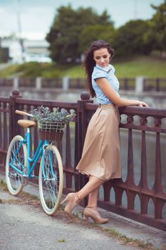 Young beautiful, elegantly dressed woman with bicycle outdoor. Beauty, fashion and lifestyle