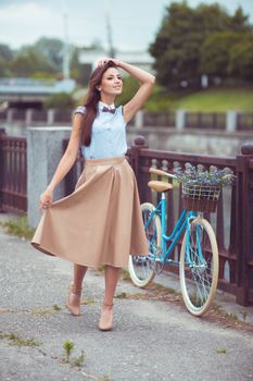 Young beautiful, elegantly dressed woman with bicycle outdoor. Beauty, fashion and lifestyle