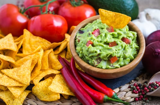 Guacamole in Wooden Bowl with Tortilla Chips and Ingredients