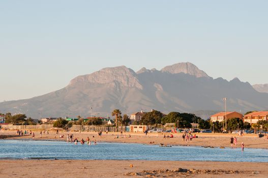 CAPE TOWN, SOUTH AFRICA - DECEMBER 17, 2014: Unidentified people at sunset on a beach in Gordens Bay with the HelderbergMountain in the back