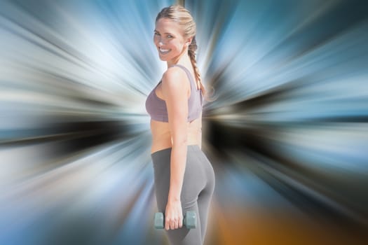 Fit woman working out with dumbbells on the beach smiling at camera against abstract background