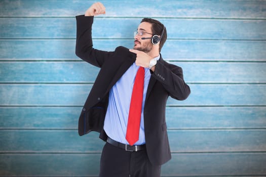 Smiling man wearing a headset while pointing his bicep against wooden planks