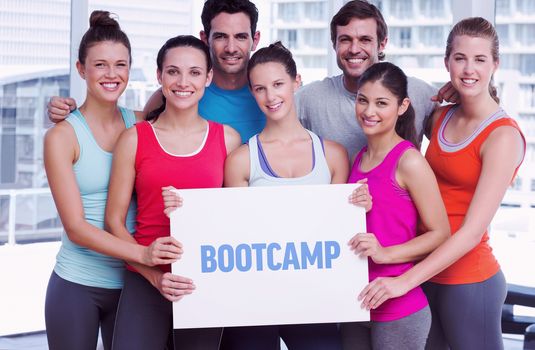 The word bootcamp against fit smiling people holding blank board