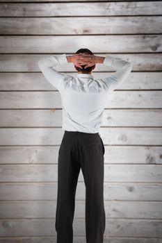 Businessman standing back to the camera with hands on head against wooden planks