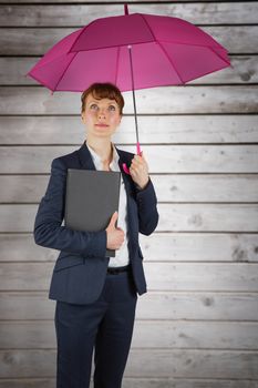 Businesswoman with umbrella against wooden planks