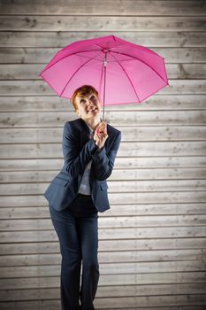 Businesswoman with umbrella against wooden planks background