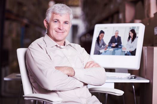 Warehouse manager using computer against smiling director sitting at the desk in front of the window between two employees