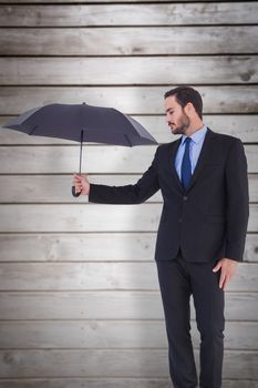 Businesswoman in suit holding umbrella against wooden planks