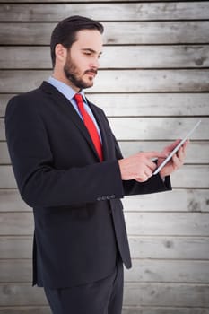 Businessman scrolling on his digital tablet against wooden planks