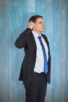 Thinking businessman scratching head against wooden planks