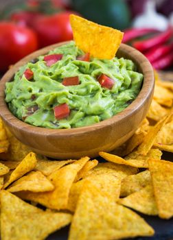 Guacamole in Wooden Bowl with Tortilla Chips and Ingredients