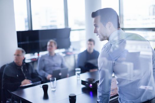 Business man making a presentation at office. Business executive delivering a presentation to his colleagues during meeting or in-house business training, explaining business plans to his employees.