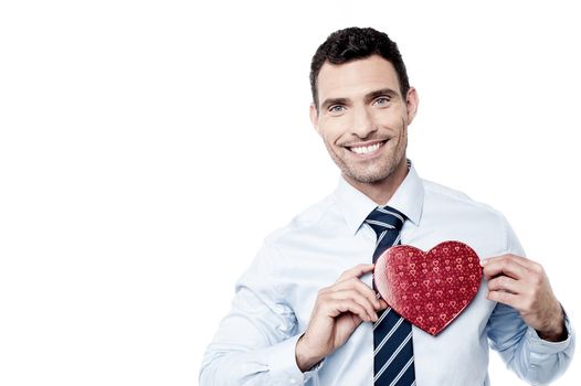 Smiling businessman showing heart shaped gift box