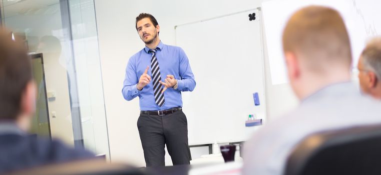 Business man making a presentation at office. Business executive delivering a presentation to his colleagues during meeting or in-house business training, explaining business plans to his employees.