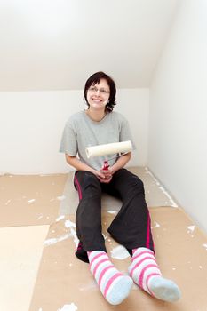 happy smiling housewife resting after painting wall to white at home