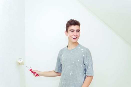 happy young teenager painting wall to white at home