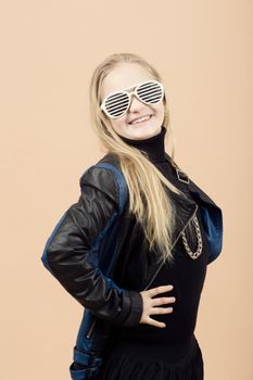 Portrait of fashion smiling european little long hair blonde girl posing in atelier with sunglasses