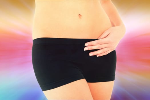 Closeup mid section of a fit woman in black shorts against abstract background