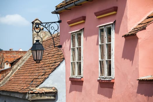 Turda, Romania - June 23, 2013: Pink facade with white windows and street lamp on an old pink house from the Old Turda city center, Romania