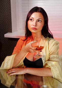 beautiful ladylove in dress on sofa with glass of brandy