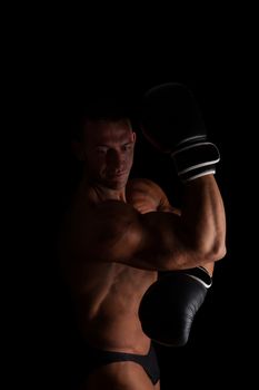 Fighter. Young sexy muscular shirtless man with boxing gloves looking into camera isolated on black background. Sport and fitness.  