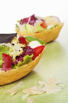 Taco shell filled with fresh colorful salad. Culinary parmigiano cheese basket.