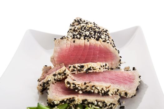 Tuna slices with white and black sesame seeds on white plate. Culinary seafood, healthy eating.