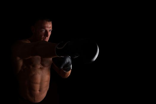 Boxer. Young sexy muscular shirtless man with boxing gloves looking into camera isolated on black background. Sport and fitness.  