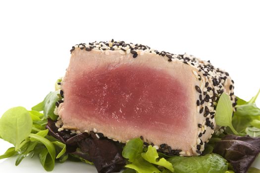 Delicious tuna steak with fresh green salad close up. Culinary seafood eating.