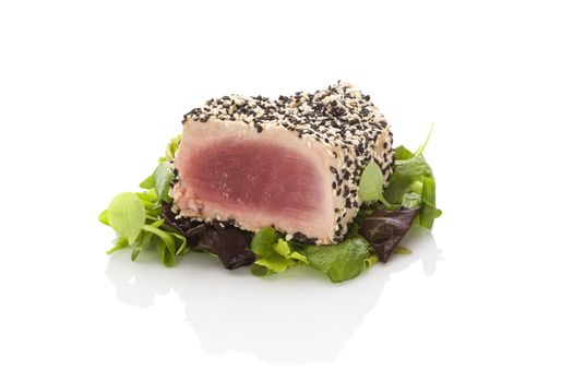 Delicious tuna steak on green salad isolated on white background. Culinary seafood eating.