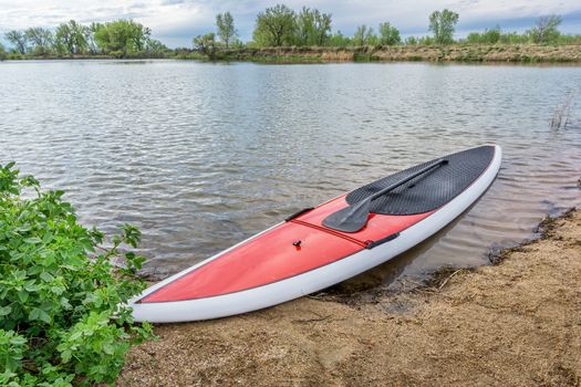 red stand up paddleboard on a lake shore in Colorado,. early spring